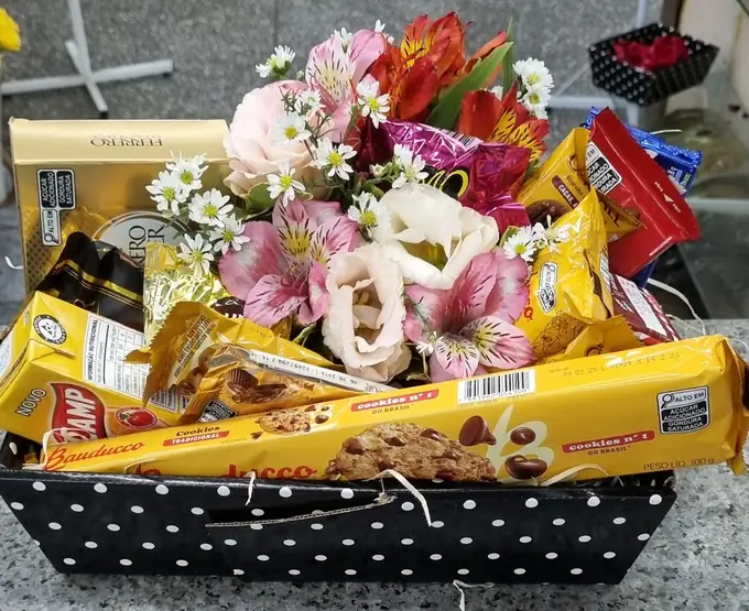 Cesta com flores cor-de-rosa, chocolates e biscoitos